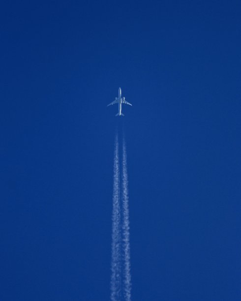 带有白色尾迹的飞行飞机:极简主义摄影图片下载