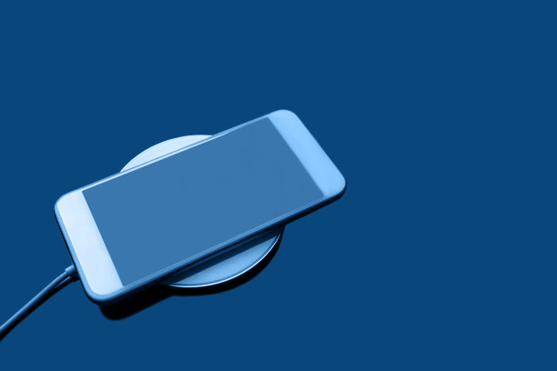 移动智能手机无线充电通过共享电池的设备在经典的蓝色。图片下载