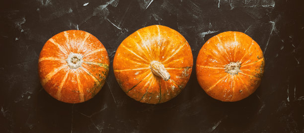 南瓜排成一行，在黑色的石头背景下，旗帜。秋天的照片。俯视图，平躺，边界。图片下载