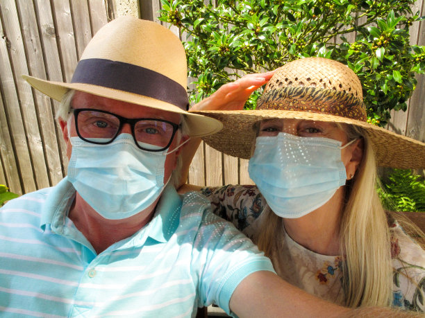 一对戴着防护面罩的老年夫妇在花园里一起自拍图片下载