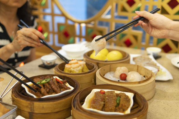 人们在餐馆里用筷子吃广东dum sum图片下载