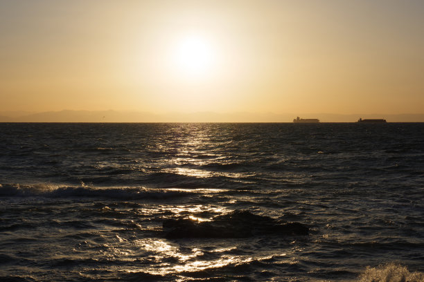 一艘船在黄昏的海面上经过图片下载