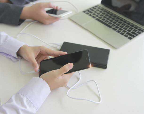 两个人将手机连接到电源。技术设备费用共享概念。图片下载