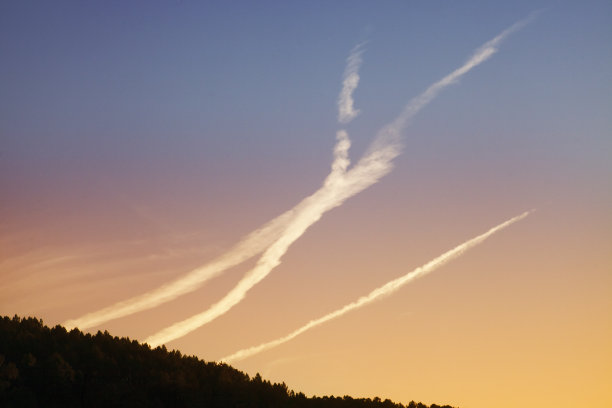 飞机蒸汽尾迹，夕阳背景。图片下载
