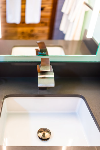 新的现代现代水龙头在浴室特写与不锈钢铬处理和白色水槽与镜子反射在房子的家垂直视图图片下载