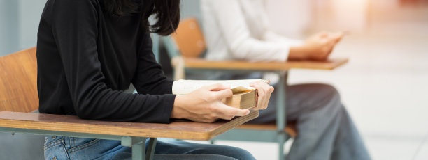 近距离观看在教室里的椅子上看书的大学生。教育库存图片。图片下载