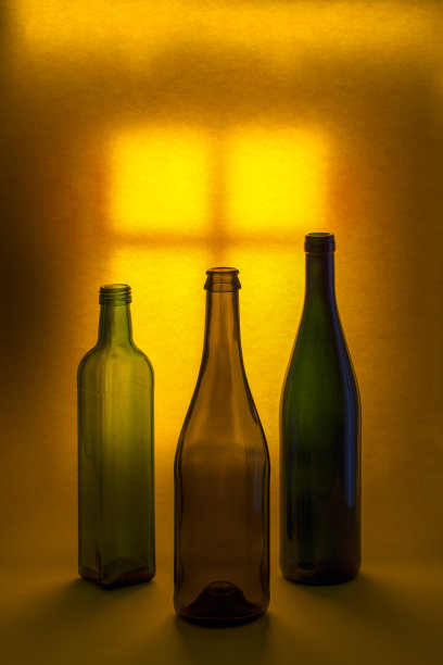 以一扇亮着灯的窗户为背景，画着彩色瓶子的静物画图片下载