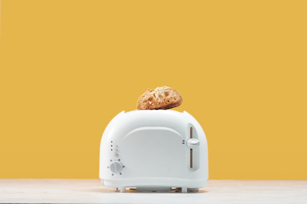 烤吐司面包弹出的面包机与黄色的墙壁图片下载