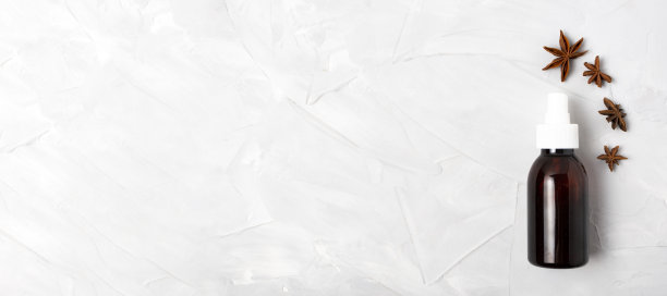 白色背景横幅上的棕色喷雾瓶。瓶子周围放着茴芹。文本。图片下载