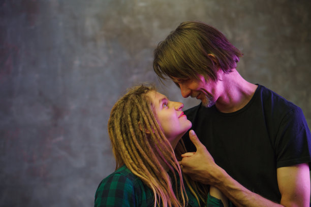 男子和年轻女子与彩色灯光在黑暗的背景摆姿势。图片下载