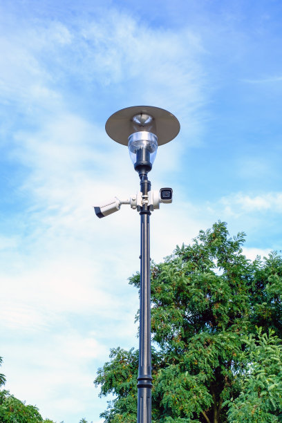 蓝色背景的金属灯柱上有两个白色的监控摄像头。图片下载