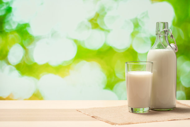 一瓶牛奶和一杯放在亚麻餐巾上的牛奶图片下载