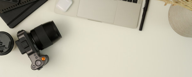摄影师工作台，相机，笔记本电脑，文具和复制空间在白色桌子上图片下载