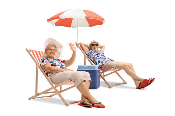 一对老年夫妇在度假时坐在帆布躺椅上，打着伞挥手图片下载
