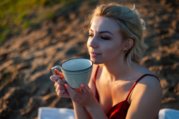 夕阳下裹着格子呢的女子手捧茶杯图片下载