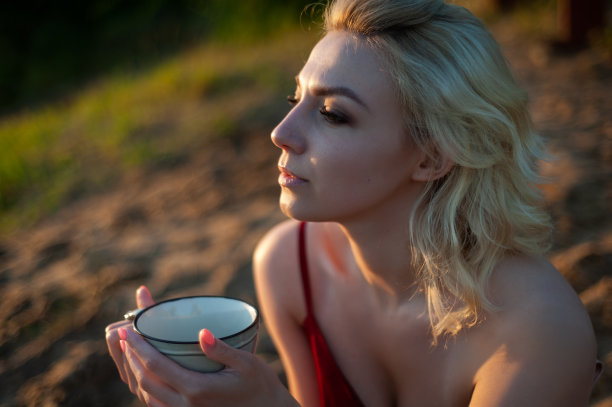 夕阳下裹着格子呢的女子手捧茶杯图片下载