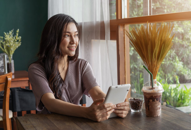 快乐的女人使用平板电脑在cafÃ©图片下载