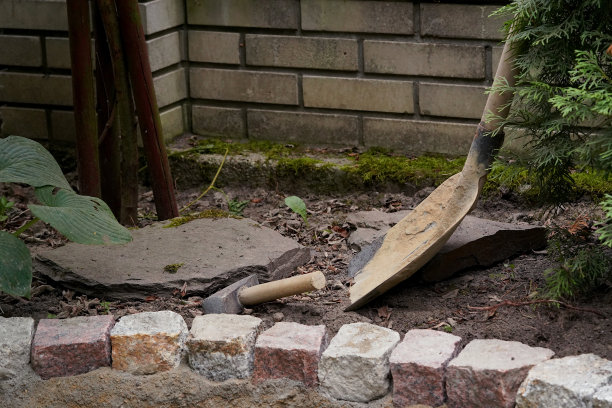 用肮脏的铁锹和锤子敲打花园里的铺路石图片下载