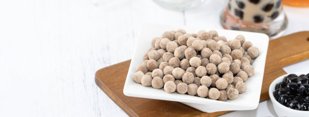 以珍珠为配料的珍珠奶茶，台湾著名饮品放在白色木桌背景的饮料杯上，近距离复制空间图片下载