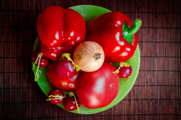 蔬菜成熟，红色的西红柿，甜椒，洋葱，萝卜在绿色盘子上特写俯视图图片下载
