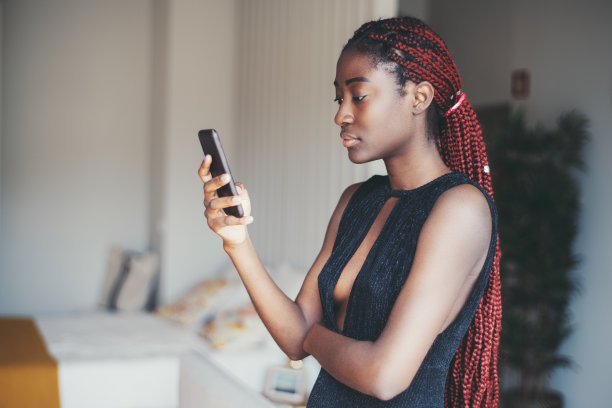 一个非洲女孩在家里用手机图片下载