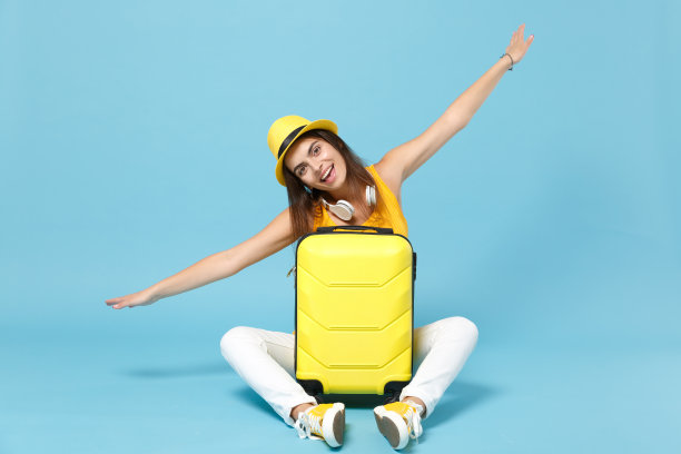 旅行者女游客黄色休闲服，帽子与手提箱照片相机孤立在蓝色背景。女乘客周末外出旅游度假。航空飞行旅程概念图片下载