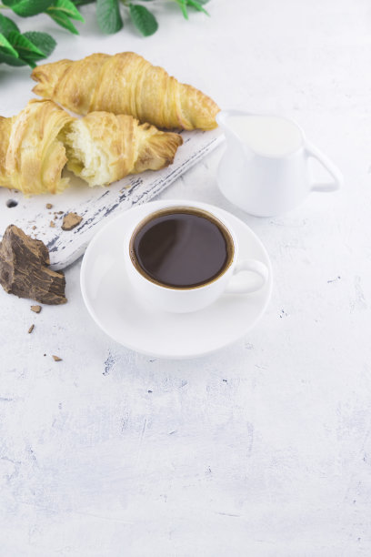 牛角面包，一杯咖啡加上一片天然可可酒，牛奶和甘蔗有机粗糖，在一个清淡的古老的普罗旺斯背景。健康的素食。食物照片与复制空间图片下载