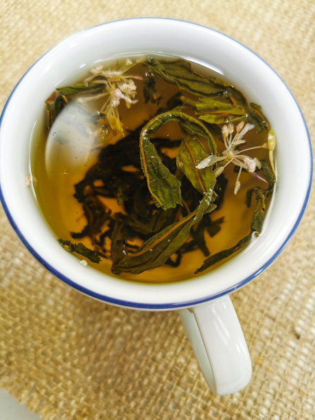 健康的生活方式的概念。将绿茶和红茶混合加入花的混合物。茶是在杯子里泡的。照片背景是粗麻布。图片下载