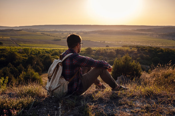 背着背包的徒步旅行者坐在山顶上图片下载