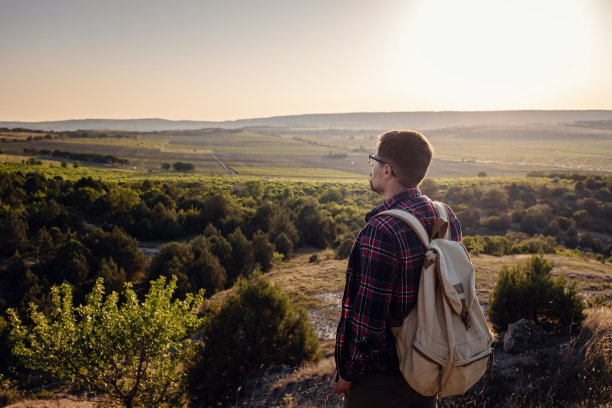 一个人在日落时站在山上。图片下载