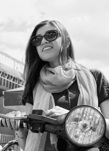 漂亮的年轻女孩坐在摩托车上。黑白照片。底部视图。旅行。图片下载