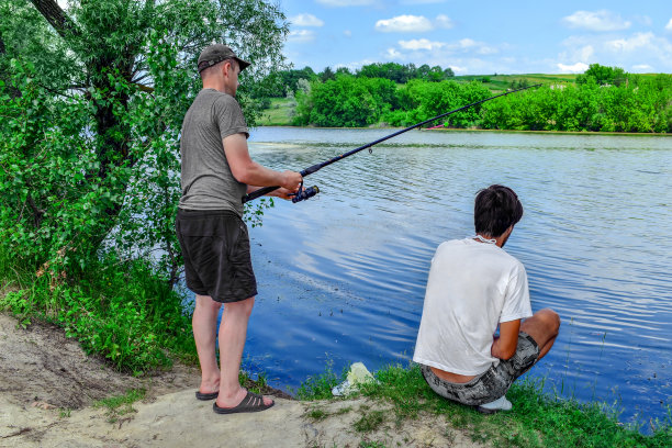 两个年轻的成年朋友在湖边钓鱼图片下载