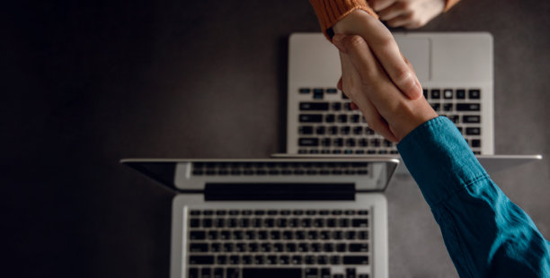 商业伙伴关系或团队合作握手。会议后的成功交易。前视图。模糊的办公桌与笔记本作为背景图片下载