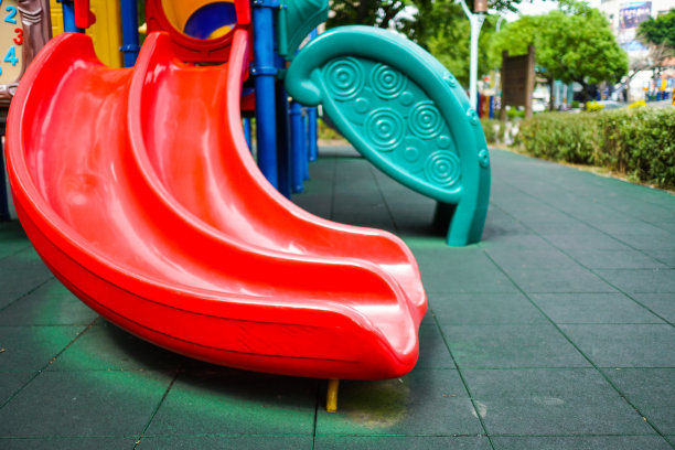 红色滑梯的特写。五颜六色的儿童游乐场。公园里的游乐设备。主题在左边。图片下载
