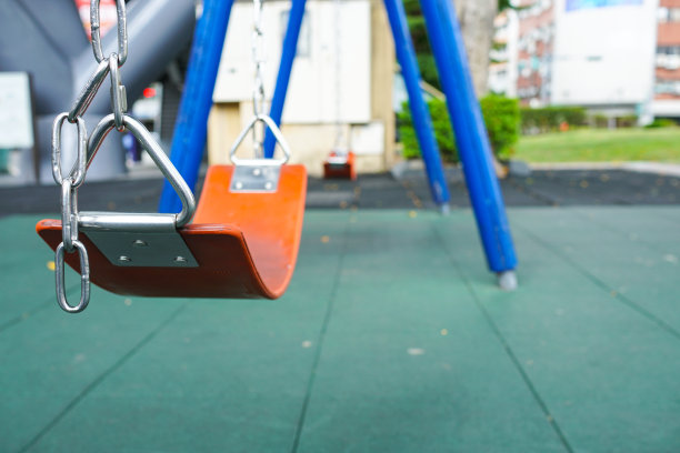 在多彩的操场上为孩子们荡秋千。公园里的游乐设备。主题在左边。图片下载