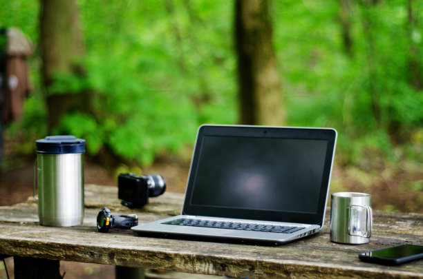 电脑咖啡杯和电话放在黑色木桌上。图片下载