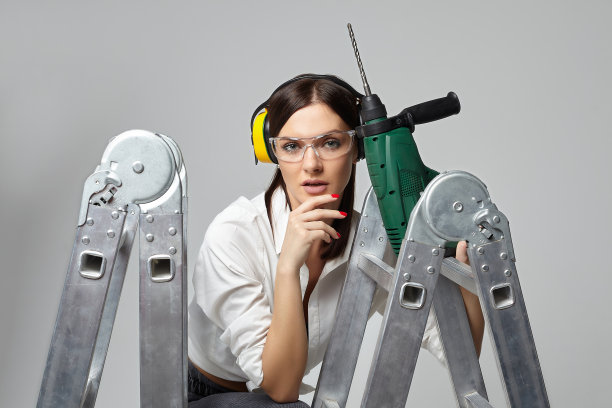 拿着钻头的建筑工女孩。家庭主妇的概念、工作工具和建筑工作……图片下载