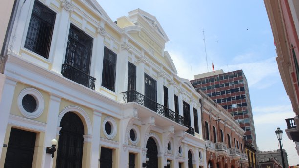 秘鲁，利马:从老城的街道上可以看到城市景观，古老的殖民时期建筑有木制阳台，白色和粉色的立面，背景是一座商业大厦图片下载