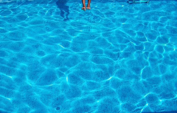 跳跃的男孩的脚即将击中宁静的蓝色的水图片下载