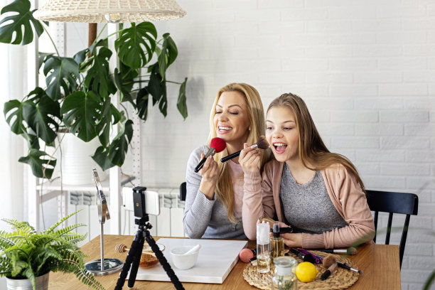 妈妈和她的女儿用化妆刷在手上录制关于化妆品的视频图片下载