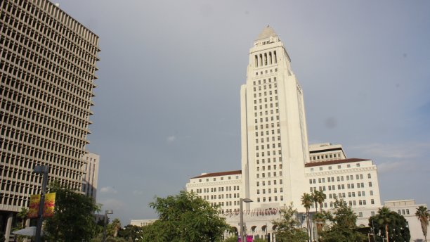 从老洛杉矶市政厅的公共公园的低角度视角，一个巨大的现代黑色混凝土建筑在一边图片下载