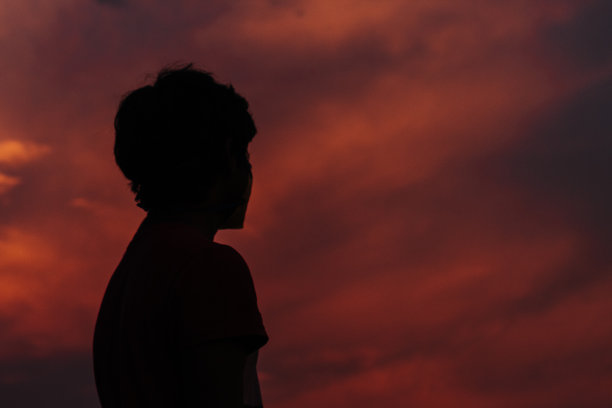 一个孩子的剪影在美丽的日落天空前图片下载
