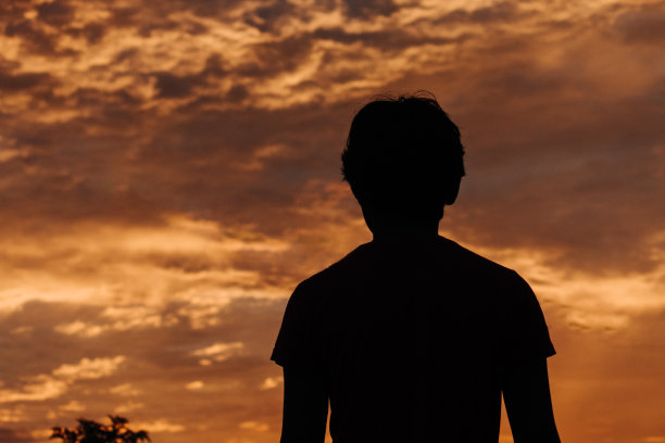 一个孩子的剪影在美丽的日落天空前图片下载