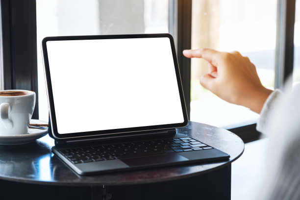 一个女人用手指着空白的桌面白色屏幕的平板电脑当做电脑图片下载