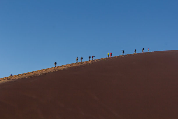 游客在日出时爬上沙丘45。这种跟踪活动在纳米比亚的纳米比亚-瑙克卢夫特国家公园的游客中很受欢迎。图片下载
