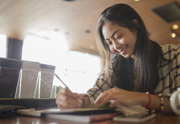 快乐微笑的女孩在用笔记本学习。自由职业，商业人士的概念图片下载