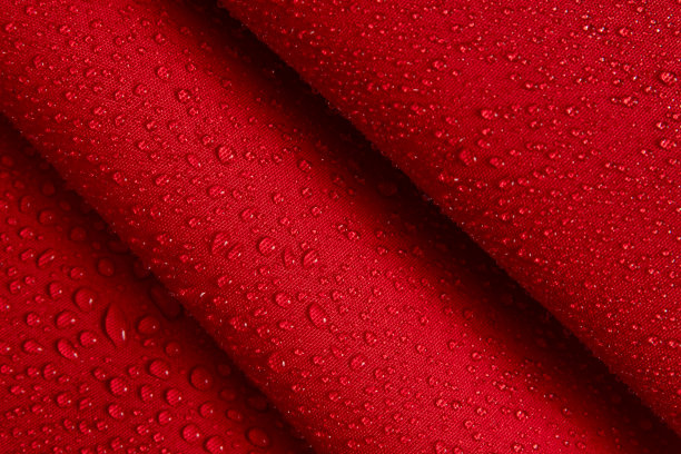 疏水性织物的抽象背景。水珠滴在皱褶的红色织物上。图片下载
