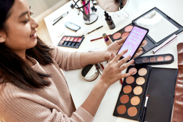 酷的应用程序。近距离的美丽博主女人广告应用程序，手持智能手机。化妆影响亚洲女孩使用应用，同时做化妆品产品评论在家图片下载