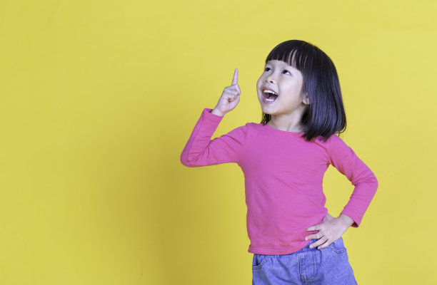 年轻的亚洲小女孩的肖像手点上孤立的黄色背景与复制空间。幼儿教育或学前班，童年生活方式回归学校观念图片下载
