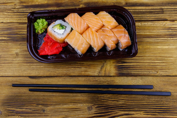 寿司卷费城在塑料盒在木桌上。前视图。装在塑料容器内的寿司供外卖或运送图片下载
